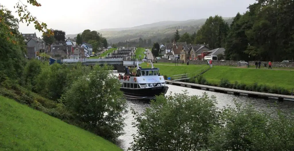 a boat traveling down a river in a town at Abbey Church 20 in Fort Augustus