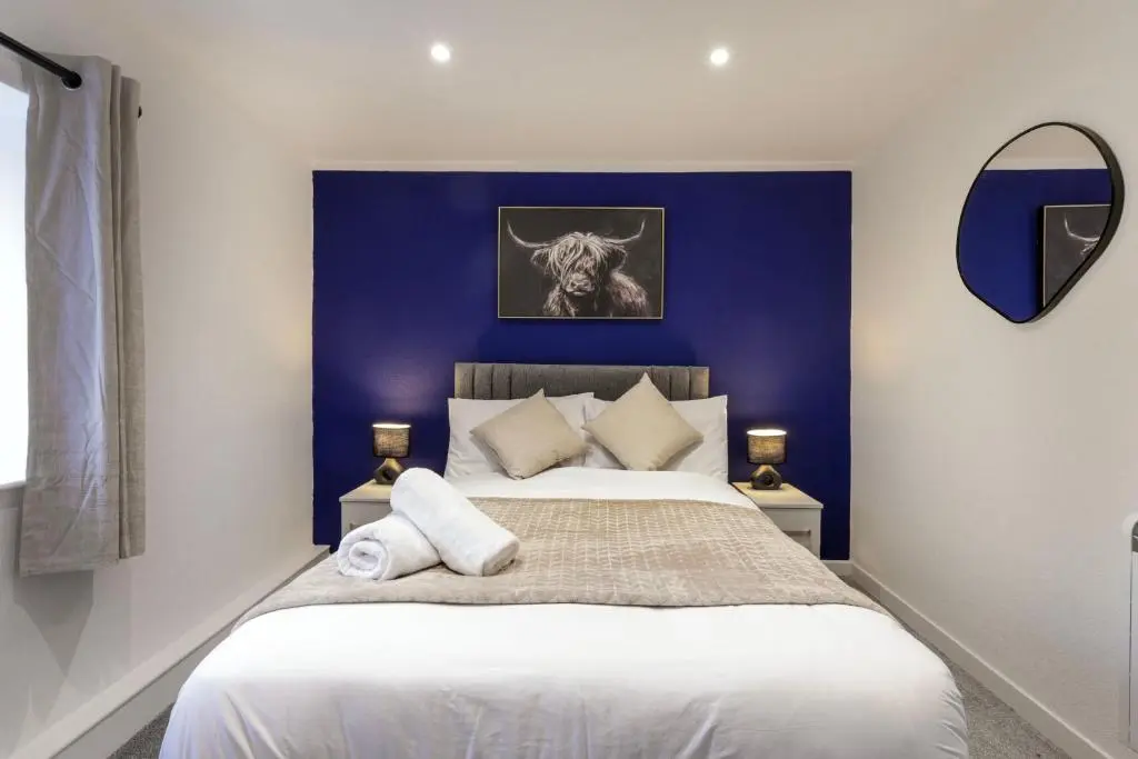 a bedroom with a large bed with a blue wall at Duffus Nights in Duffus