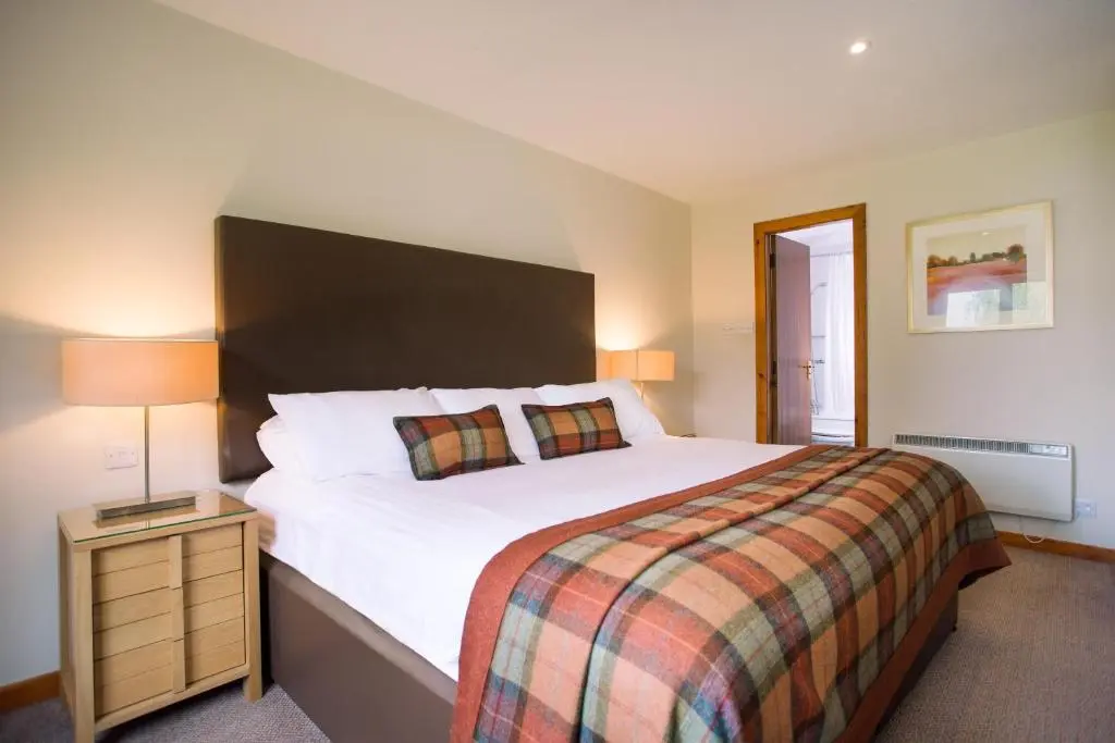 a bedroom with a large bed and a night stand at Macdonald Spey Valley Resort in Aviemore