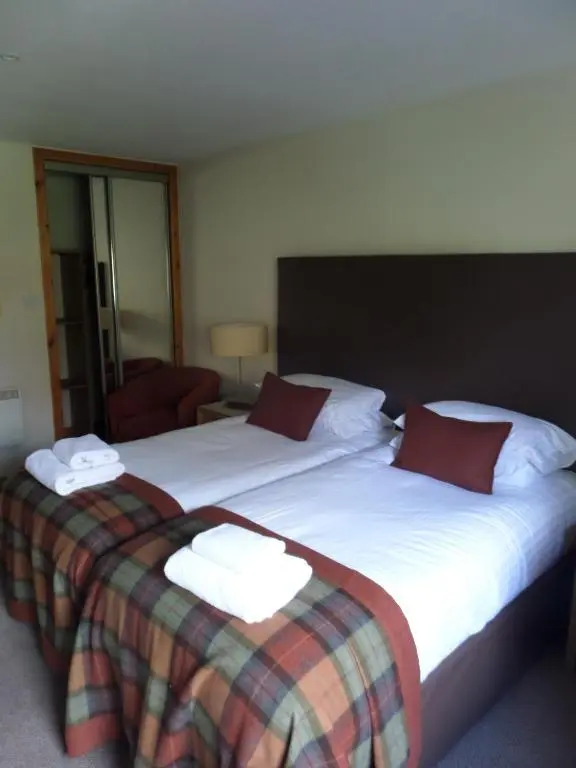 two beds in a hotel room with towels on them at Macdonald Spey Valley Resort in Aviemore