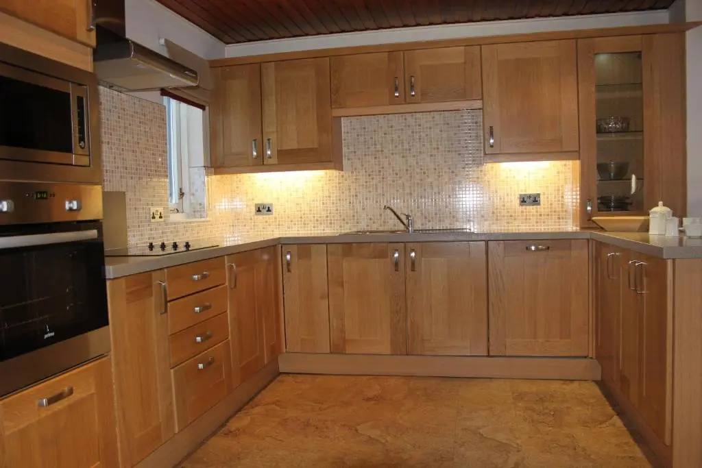 a large kitchen with wooden cabinets and a sink at Macdonald Spey Valley Resort in Aviemore