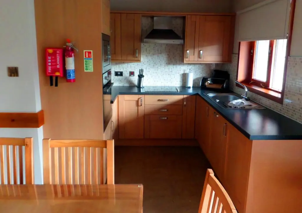 a kitchen with wooden cabinets and a table and a sink at Macdonald Spey Valley Resort in Aviemore