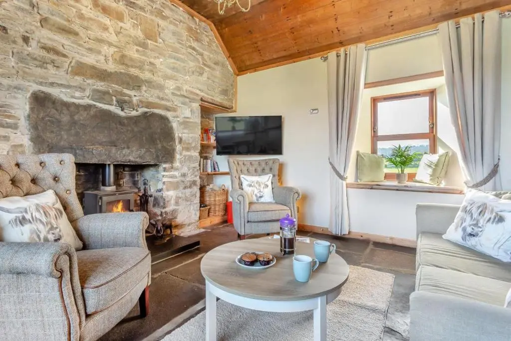 a living room with a stone fireplace and a table at 1 Bed in Wick oc-b33442 in Wick