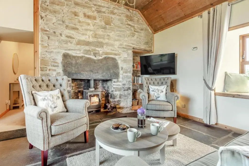 a living room with a stone fireplace and two chairs and a table at 1 Bed in Wick oc-b33442 in Wick