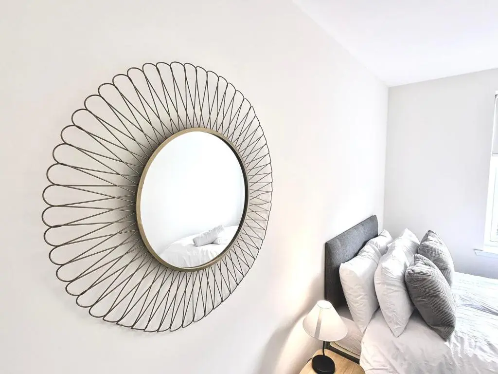 a mirror hanging on a wall next to a bed at Picturesque Tornagrain Apartment 2bed Free Parking WiFi - Near Inverness Airport