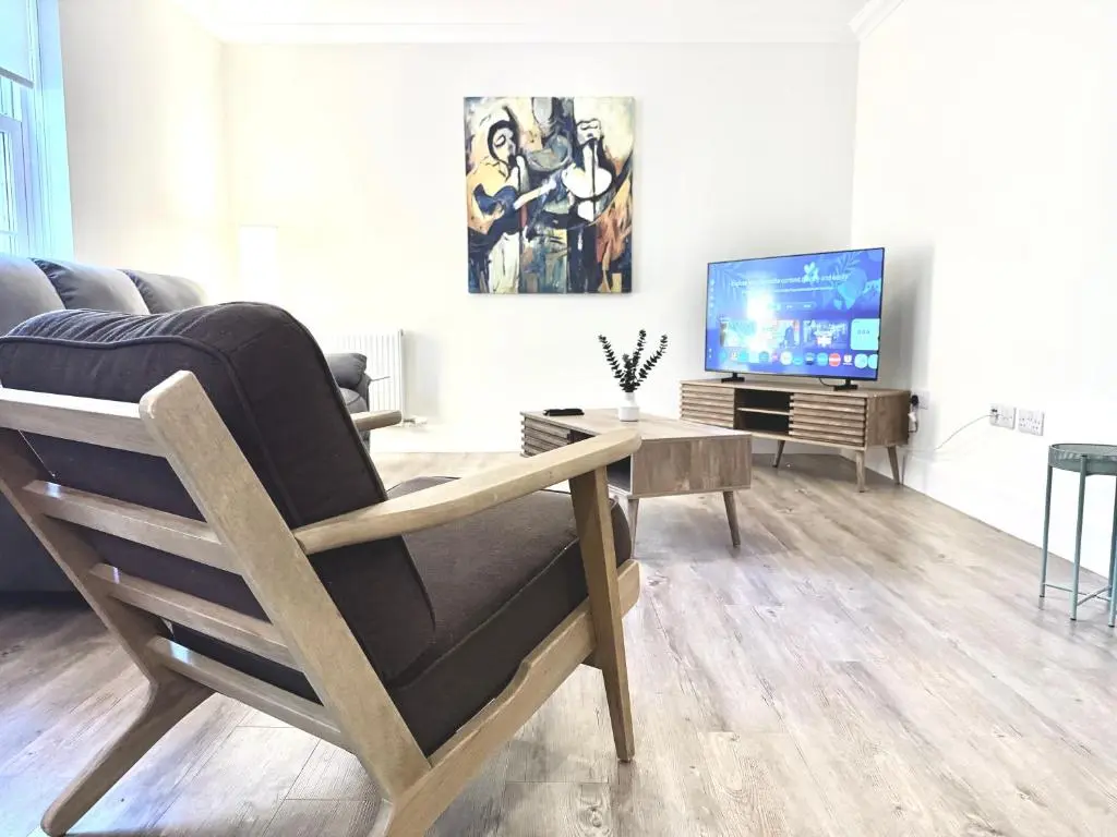 a living room with a chair and a television at Picturesque Tornagrain Apartment 2bed Free Parking WiFi - Near Inverness Airport