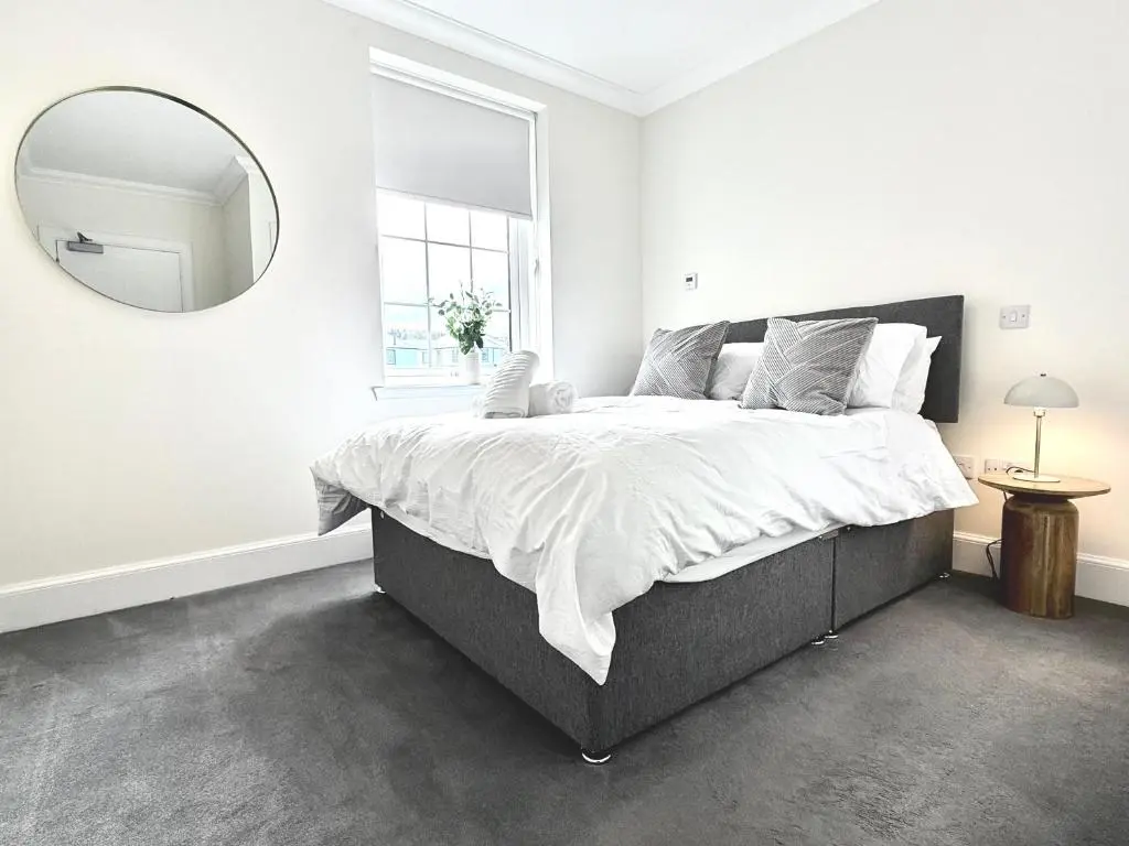 a white bedroom with a large bed and a mirror at Picturesque Tornagrain Apartment 2bed Free Parking WiFi - Near Inverness Airport
