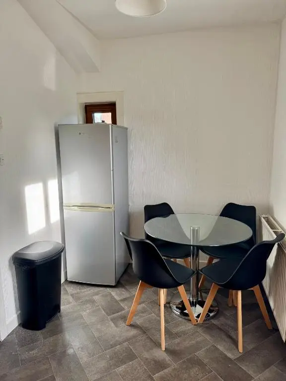 a table and chairs in a room with a refrigerator at Bruce Gardens Home in Inverness