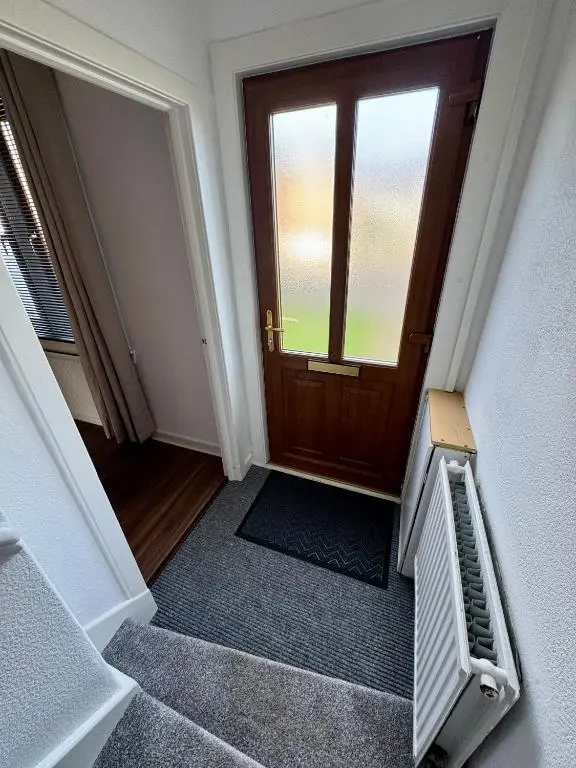 an empty hallway with a wooden door and a staircase at Bruce Gardens Home in Inverness