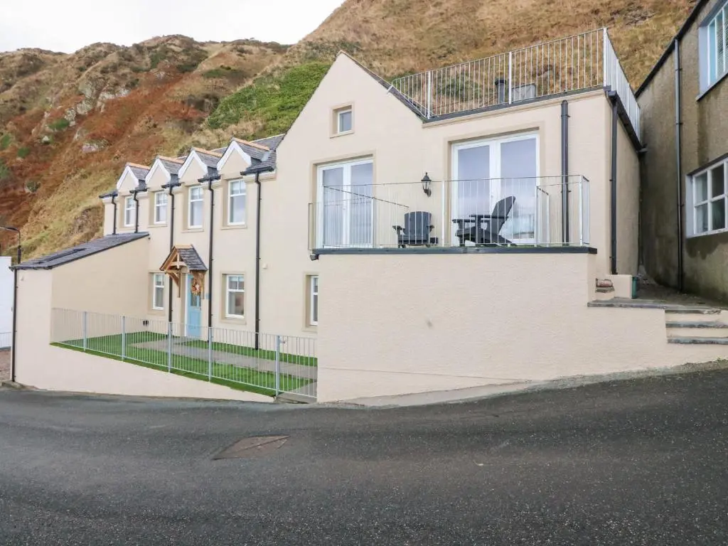 a house with a balcony with two chairs on it at The Old Kipper Hoose in Banff