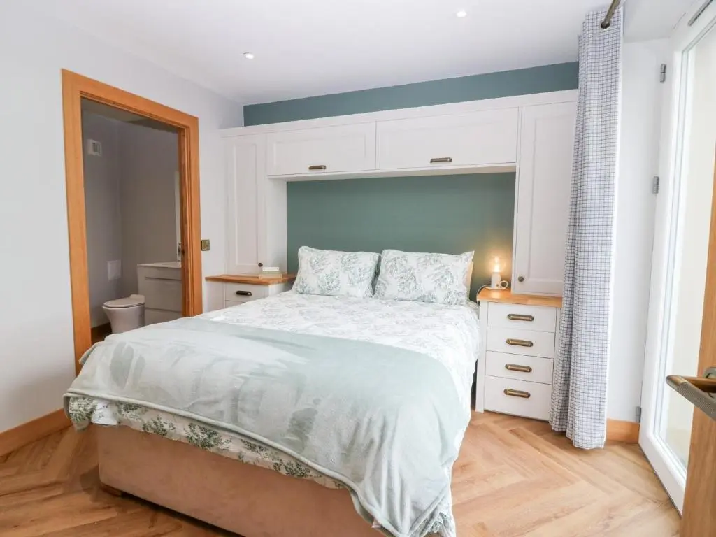 a bedroom with a large bed with a blue headboard at The Old Kipper Hoose in Banff