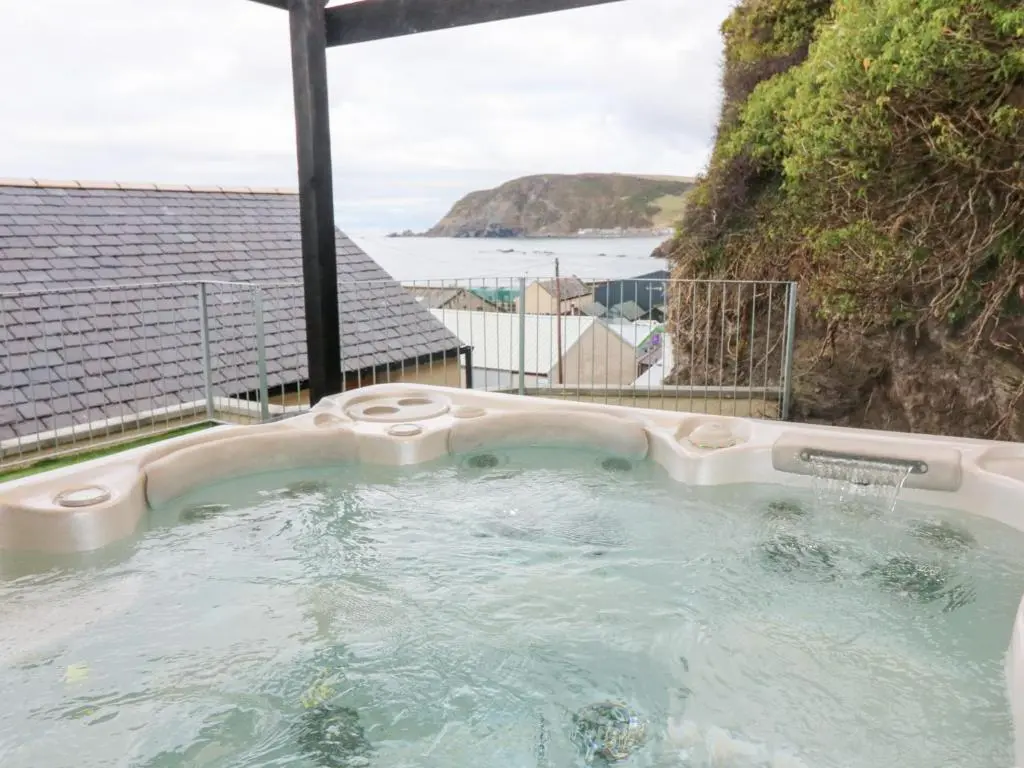 a hot tub with a view of the ocean at The Old Kipper Hoose in Banff
