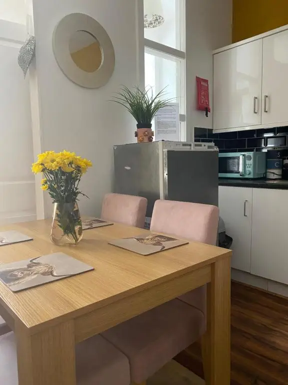 a wooden table with chairs and a vase of flowers at Cozy one bedroom apt in Inverness
