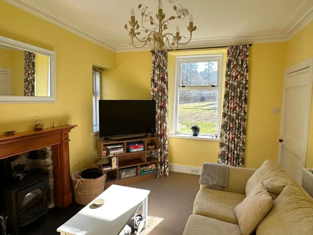 a living room with a couch and a tv at Cosy Cottage on the Whisky Trail in Haugh of Glass