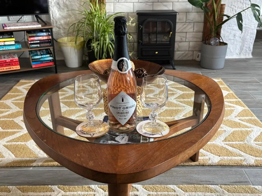 a bottle of wine and two glasses on a table at Smiddy Cottage in Portmahomack