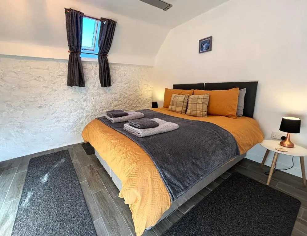 a bedroom with a bed with two towels on it at Smiddy Cottage in Portmahomack