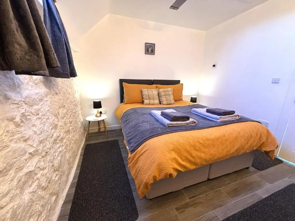 a bedroom with a bed with towels on it at Smiddy Cottage in Portmahomack