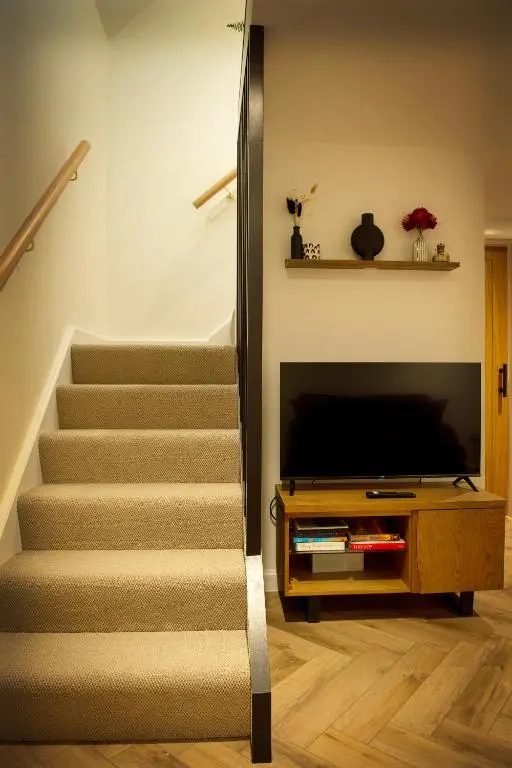 a staircase in a living room with a television at Coorie-In Cottage in Whitehills
