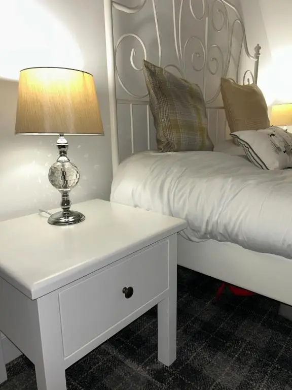 a bedroom with a bed and a table with a lamp at Glenburn Cottage in Kirkmichael