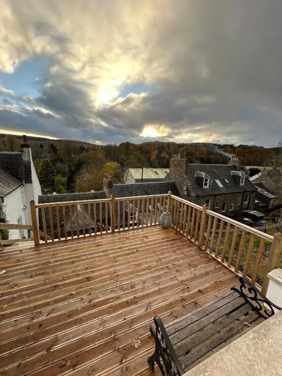 a wooden deck with a bench on a balcony at Glenburn Cottage in Kirkmichael