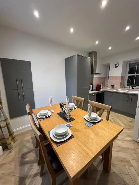 a kitchen with a wooden table with chairs and a dining room at Glenburn Cottage in Kirkmichael