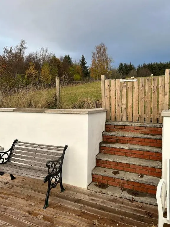 a bench sitting on a deck next to a fence at Glenburn Cottage in Kirkmichael