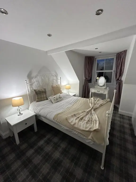 a bedroom with a white bed and a window at Glenburn Cottage in Kirkmichael