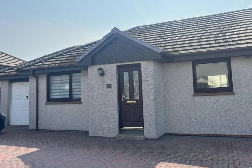 a house with a brown door on a brick driveway at The Burghead Hideaway in Burghead
