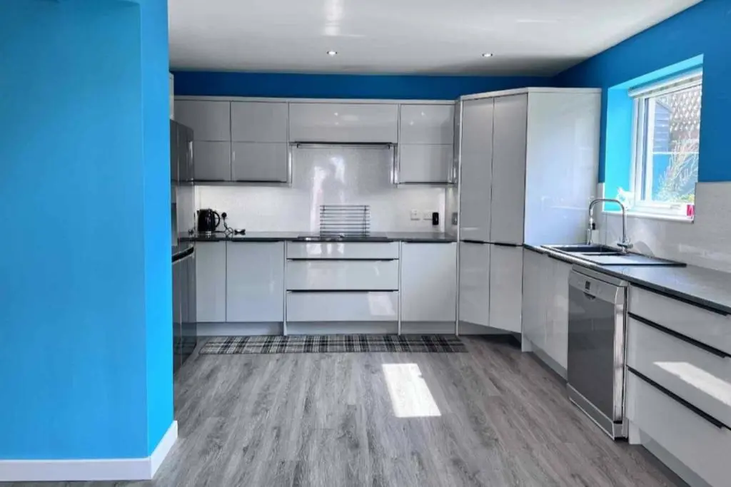 a large kitchen with white cabinets and blue walls at The Burghead Hideaway in Burghead