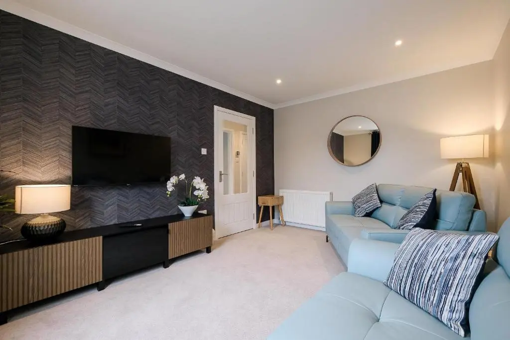 a living room with a blue couch and a flat screen tv at High Street Retreat in Inverurie
