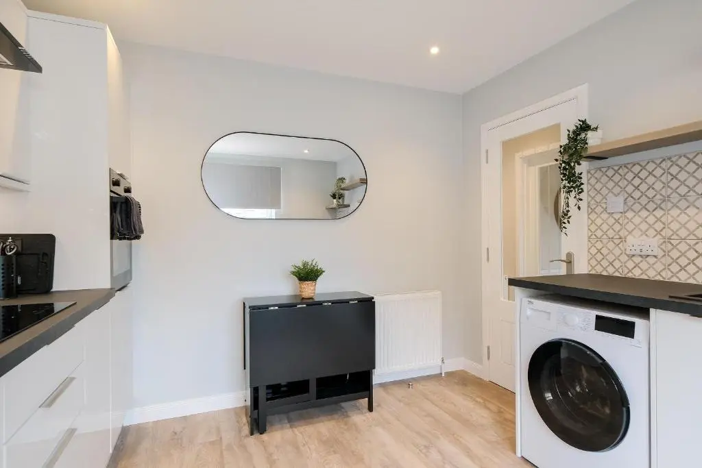 a laundry room with a washing machine and a mirror at High Street Retreat in Inverurie