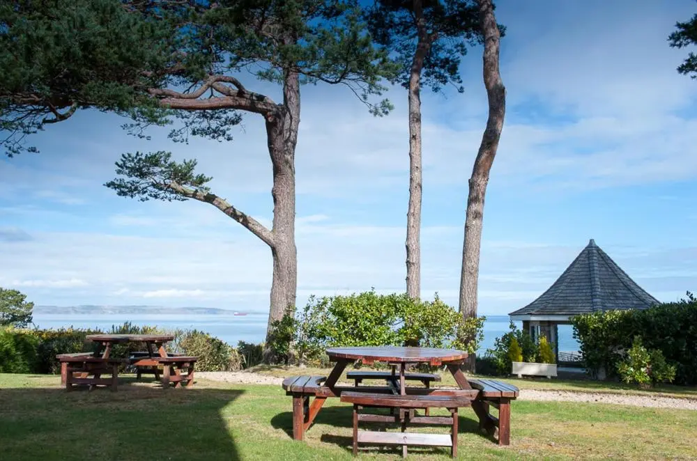 two picnic tables in a park with a view of the ocean at The Bunker Self Catering in Nairn
