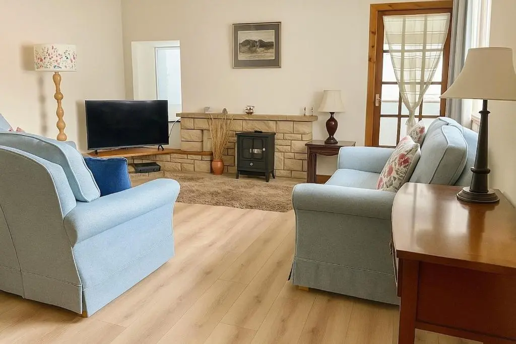a living room with two chairs and a television at Beachy Days and Family Stays in Nairn