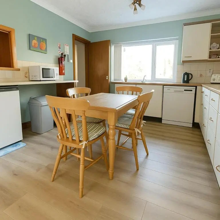 a kitchen with a wooden dining table and chairs at Beachy Days and Family Stays in Nairn