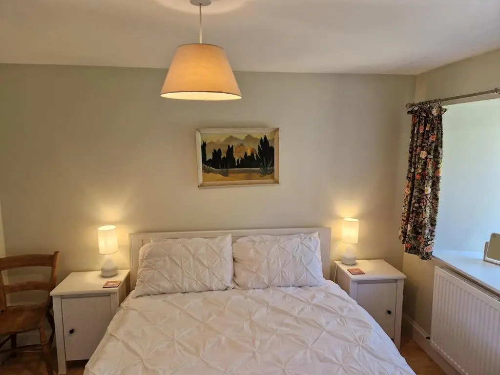a bedroom with a bed with two tables and two lamps at Highland River Cottage with Hot Tub in Evanton