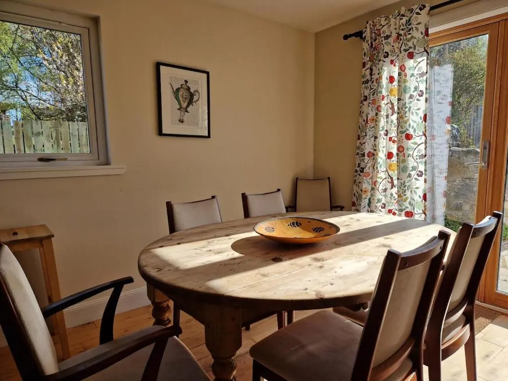 a dining room with a wooden table and chairs at Highland River Cottage with Hot Tub in Evanton