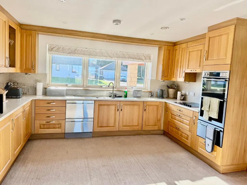 a kitchen with wooden cabinets and a window at Golf View Spacious Bungalow 2 Bathrooms, Free Parking WiFi in Elgin