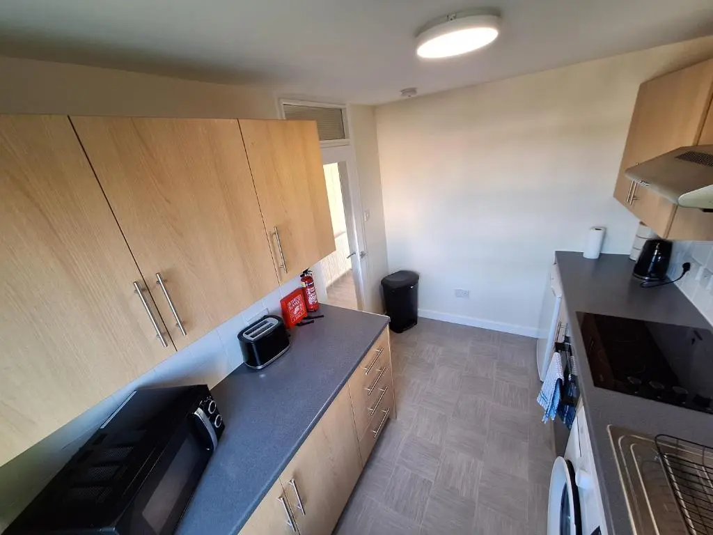 a kitchen with wooden cabinets and a black counter top at Spacious Two Bed Close To City Centre!! in Dalneigh