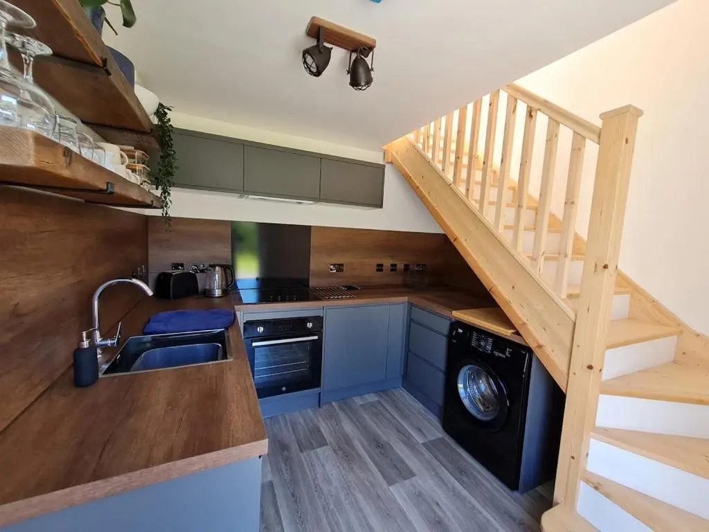 a kitchen with a sink and a staircase with a dishwasher at Woodland studio in Stittenham