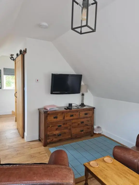 a living room with a tv on the wall at Woodland studio in Stittenham