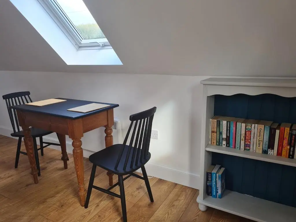 a room with a table and chairs and a book shelf at Woodland studio in Stittenham