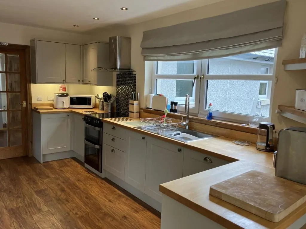 a kitchen with white cabinets and a large window at Oiseval in Fort Augustus