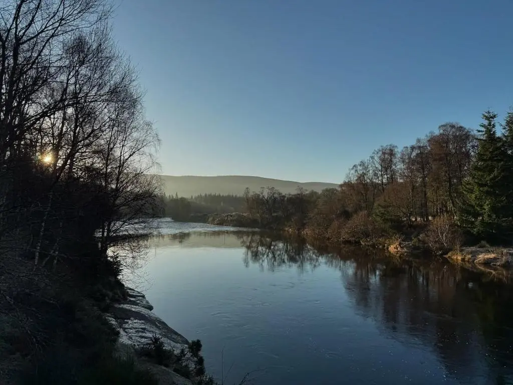 a river with the sun reflecting on the water at Beautiful dog friendly lodge with hot tub in Aboyne