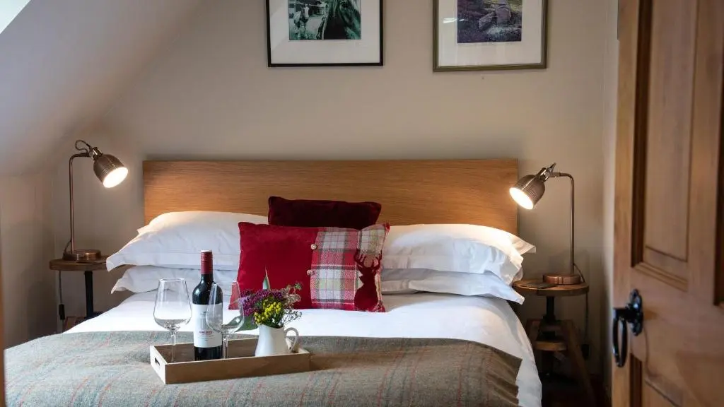 a bedroom with a bed with two bottles of wine and two glasses at Beautiful dog friendly lodge with hot tub in Aboyne