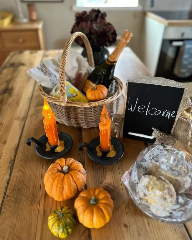 a table with pumpkins and a basket with a bottle of wine at Beautiful dog friendly lodge with hot tub in Aboyne