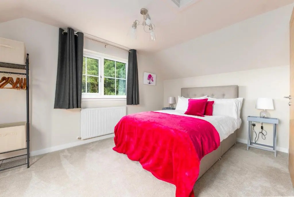 a bedroom with a large bed with a red blanket at Linden House in Fortrose