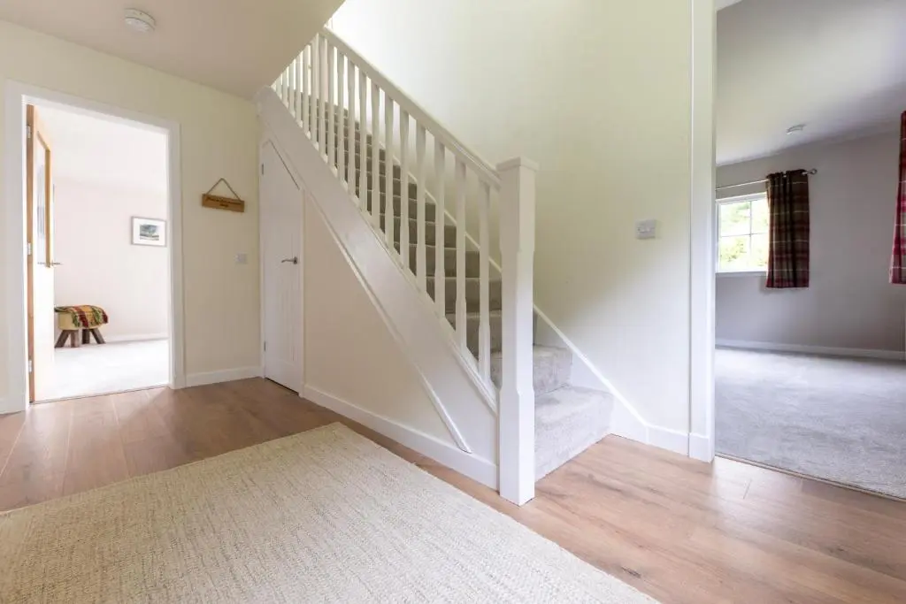 a white staircase in a home with white walls at Linden House in Fortrose