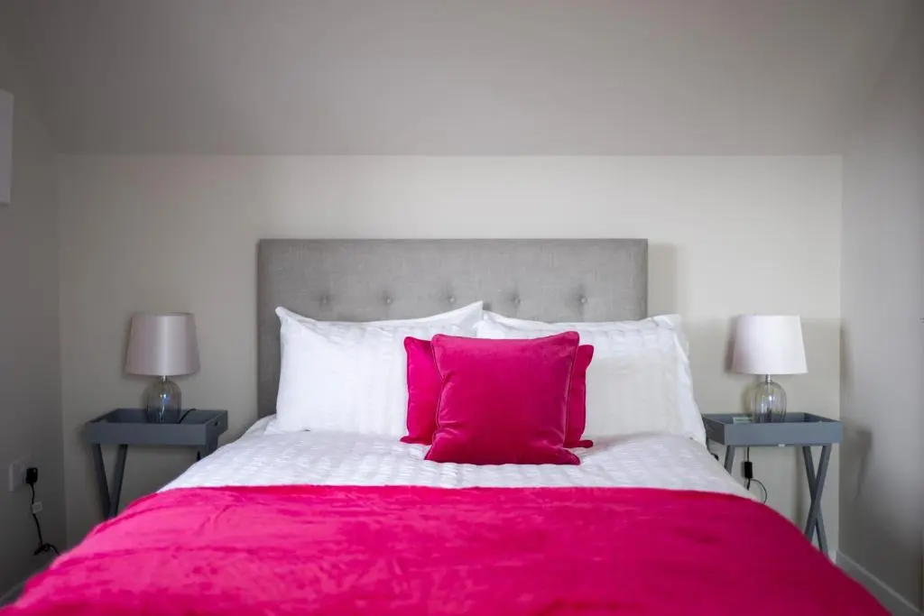 a large bed with a red blanket and two night stands at Linden House in Fortrose