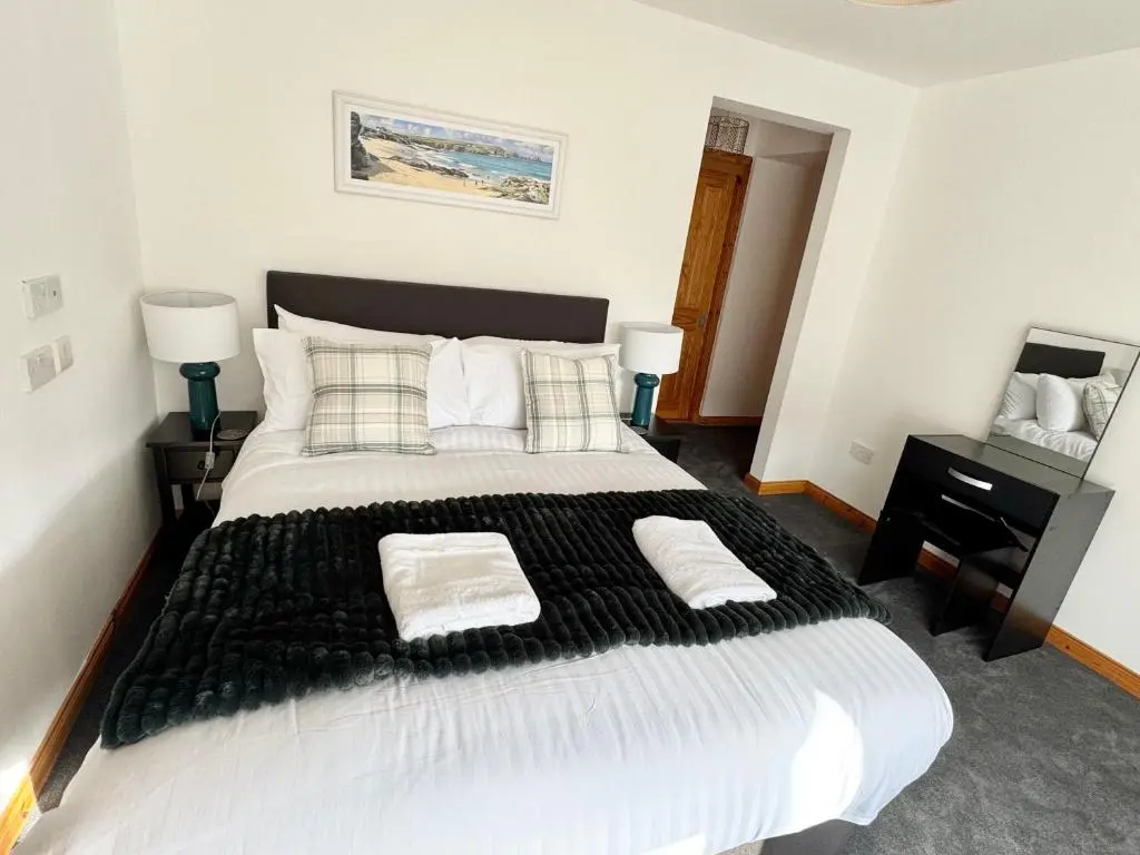a bedroom with a large bed with black and white sheets at Suites Holiday Home Inverness in Inverness
