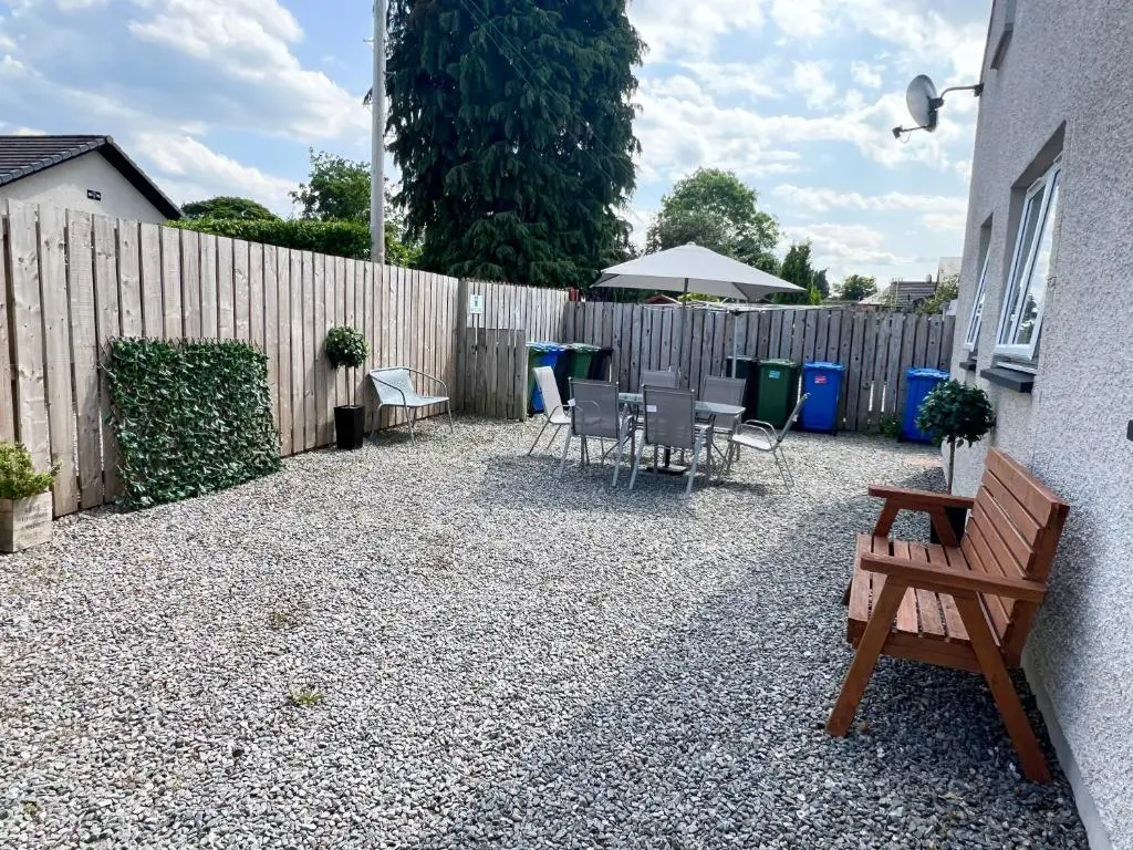 a patio with a bench and chairs and a fence at Suites Holiday Home Inverness in Inverness